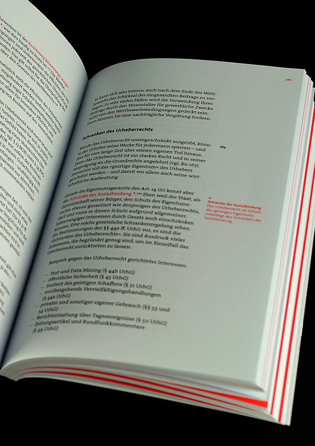  Aufgeschlagene rechte Buchseite mit schwarzem und rotem Text.